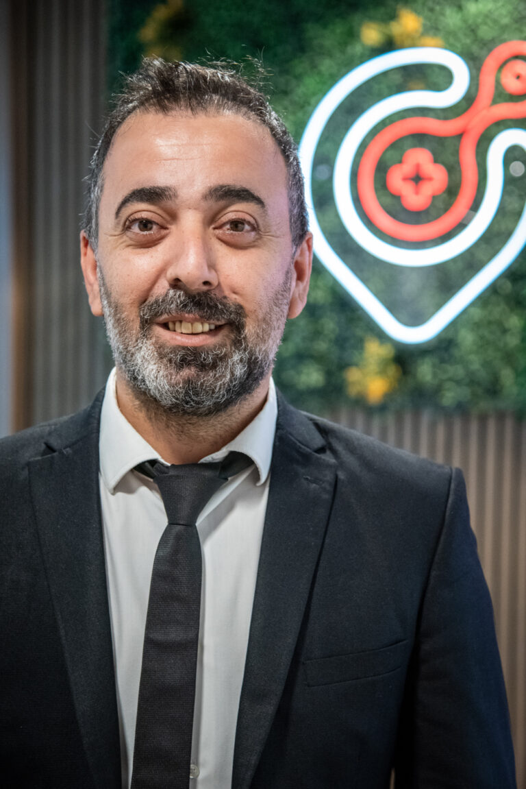 Smiling man in suit in front of neon red logo