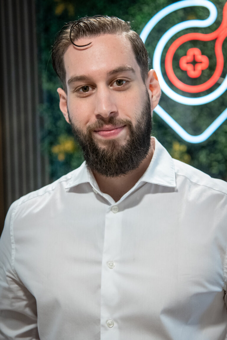 Man in white shirt in front of neon light logo