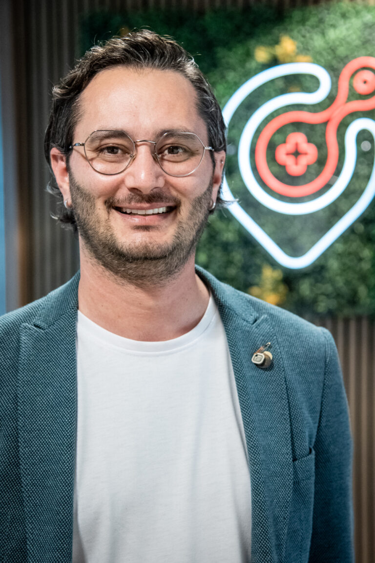 Smiling man with glasses in front of neon sign